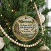 A round ornament hanging on a Christmas tree, featuring a scenic landscape with a river and mountains.