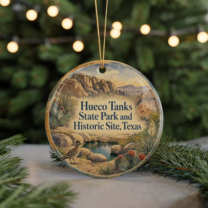 A round ornament with a scenic image of a desert landscape, featuring a bird, cacti, and mountains, along with the text "Hueco Tanks State Park and Historic Site, Texas".