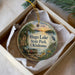 A decorative ornament in a box, featuring a scenic landscape with a lake, boat, and birds, along with the text "HUGO LAKE STATE PARK, OKLAHOMA".