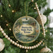 A round ornament hanging on a Christmas tree, featuring a scenic image of a park with a lake, bridge, and wildlife.