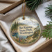A decorative ornament with a scenic landscape of mountains, pine trees, and a body of water, hanging from a string.