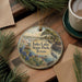 A decorative ornament featuring a serene landscape of Inks Lake State Park, Texas, with a bird in the foreground and pine branches surrounding it.