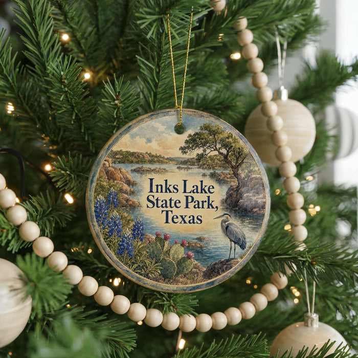 A circular ornament hanging on a Christmas tree, featuring a scenic landscape with a lake, mountains, and a bird.
