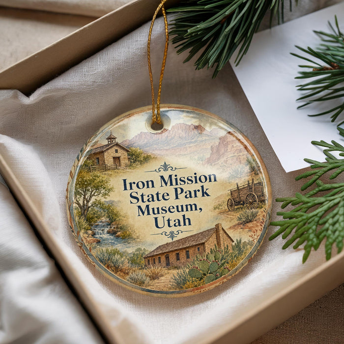 A decorative ornament with a scenic landscape of Iron Mission State Park Museum, Utah, featuring a small house, a wagon, and a stream.