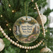 A round ornament hanging on a Christmas tree, featuring a scenic landscape with a waterfall and a castle.