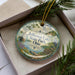 A decorative ornament in a box, featuring a scenic image of Jefferson Lake State Park, Ohio.