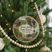 A round ornament hanging on a Christmas tree, featuring a scenic landscape with a waterfall and forest.