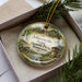 A decorative ornament with a scenic image of Johnsonville State Historic Park in Tennessee, featuring a cabin, a river, and pine trees.