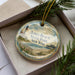 A decorative ornament in a box, featuring a lighthouse and beach scene with the text "Jones Beach State Park New York".