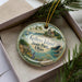 A decorative ornament in a box, featuring a scenic image of Kelley's Island State Park, Ohio.