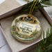 A decorative ornament with a scenic image of Kickapoo Canyon State Park, Texas, is displayed in a box with pine branches.