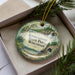 A decorative ornament with a scenic landscape of Kinnickinnic State Park, Wisconsin, featuring a waterfall and pine trees.