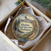 A decorative ornament in a box, featuring a scenic landscape with mountains, a waterfall, and a path leading through the wilderness.
