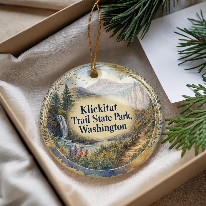A decorative ornament with a scenic landscape of mountains, waterfalls, and pine trees, hanging from a string.