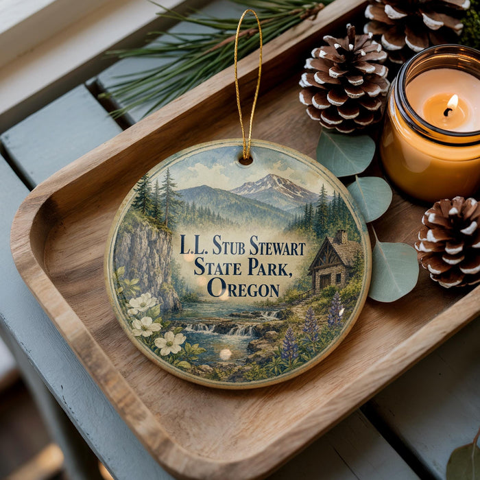 A wooden tray with a decorative ornament featuring a scenic landscape of mountains, pine trees, and a cabin, along with pine cones and a lit candle.