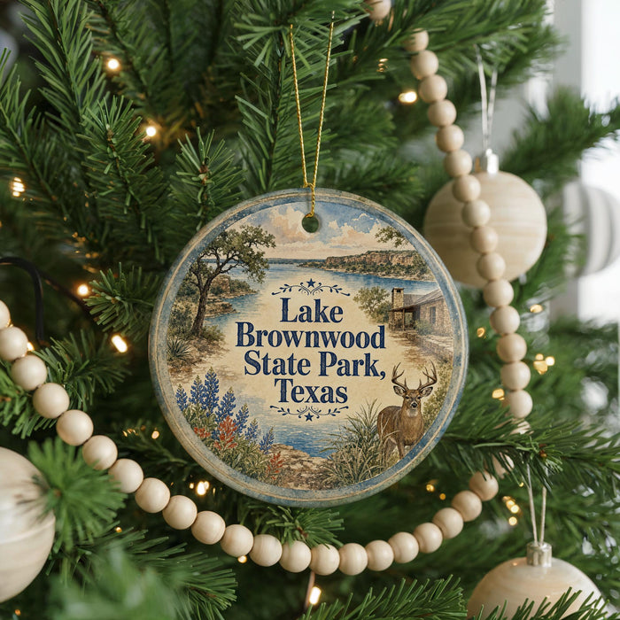 A round ornament hanging on a Christmas tree, featuring a scenic image of Lake Brownwood State Park in Texas.