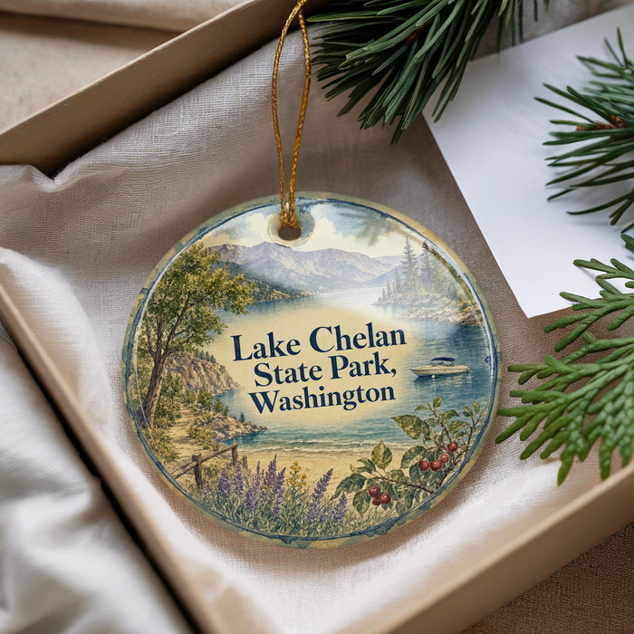 A decorative ornament with a scenic landscape of Lake Chelan State Park, Washington, featuring a boat on the water and pine trees in the background.