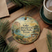A round ornament with a scenic landscape of Lake, Colorado City, State Park, and Texas, featuring a desert and a lake, is displayed on a wooden surface alongside a cup of coffee and some pine branches.