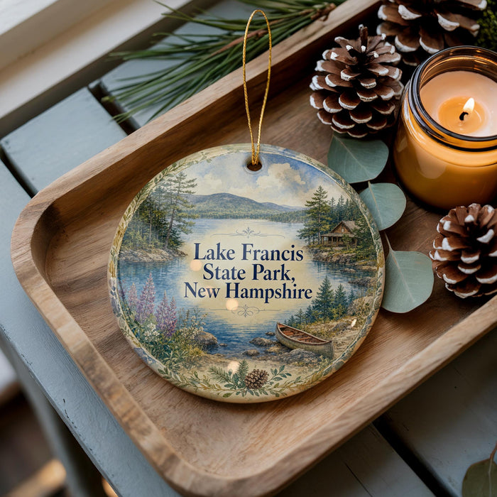 A decorative ornament featuring a scenic lake surrounded by pine trees and mountains, with the text "Lake Francis State Park, New Hampshire" displayed prominently.