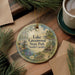 A round ornament with a scenic image of Lake Greenwood State Park, South Carolina, hanging on a wooden surface.