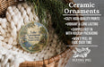 Ceramic ornaments, featuring a lake and wooded area, are displayed in a basket with a pine tree branch.