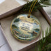 A decorative ornament with a scenic landscape of Lake Mary Ronan State Park, Montana, featuring a lake, mountains, and pine trees.