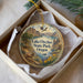 A decorative ornament in a white box, featuring a scenic landscape with mountains, a lake, and a bird in flight.