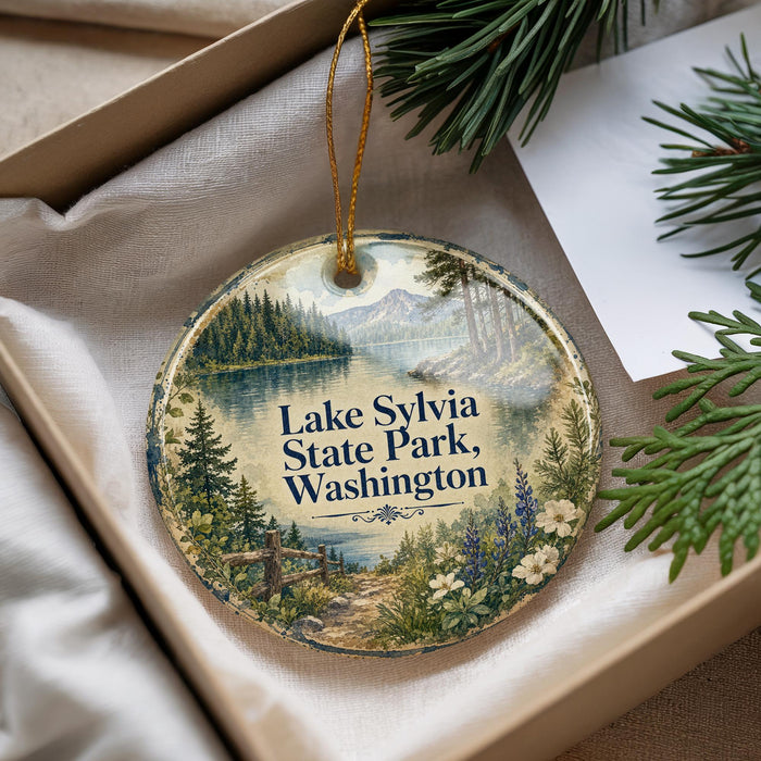 A decorative ornament with a scenic landscape of Lake Sylvia State Park, Washington, featuring pine trees, a lake, and mountains.