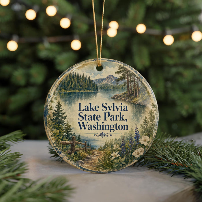 A round ornament with a scenic landscape of Lake Sylvia State Park, Washington, featuring a lake, mountains, pine trees, and flowers.