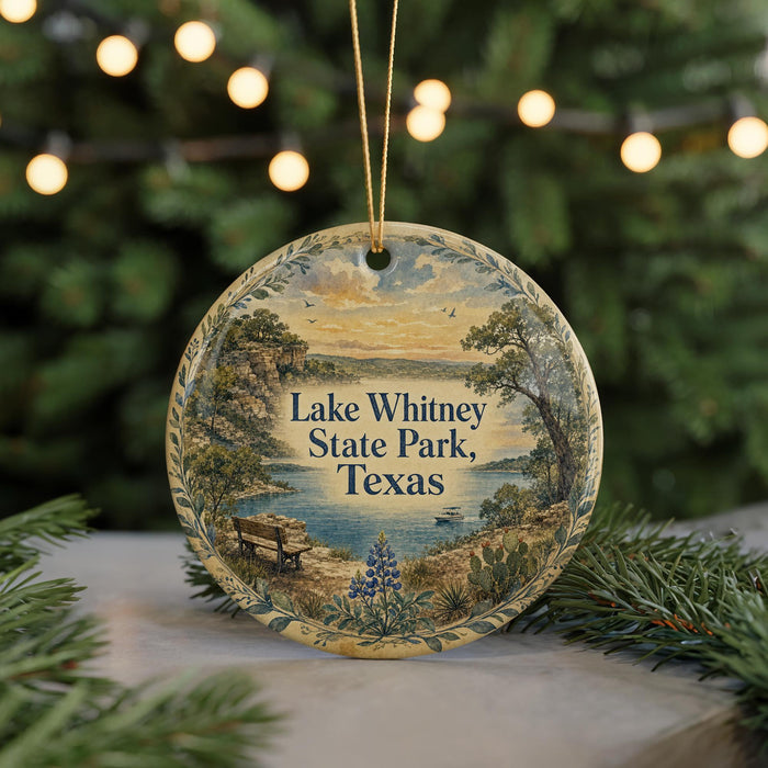 A round ornament with a scenic landscape of Lake Whitney State Park, Texas, featuring a bench, trees, and a body of water.
