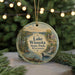 A round ornament featuring a scenic landscape of Lake Wissota State Park, Wisconsin, with a bird in the foreground and a waterfall in the background.