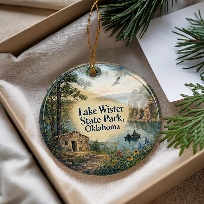 A decorative ornament featuring a scenic landscape with a lake, mountains, and a small cabin, hanging from a string.
