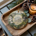 A decorative ornament featuring a scenic landscape of Laurel Mountain State Park, Pennsylvania, with a candle and pine cones on a wooden tray.