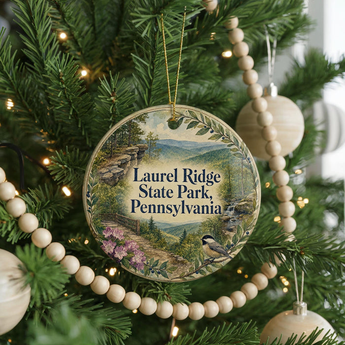 A round ornament hanging on a Christmas tree, featuring a scenic image of Laurel Ridge State Park in Pennsylvania.
