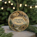 A circular ornament featuring a scenic landscape with mountains, trees, and a river, hanging from a string.