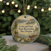A round ornament with a scenic landscape and two figures, hanging from a string.