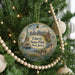 A round ornament hanging on a Christmas tree, featuring an illustration of Liberty State Park in New Jersey with the Statue of Liberty in the background.
