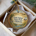 A decorative ornament in a box, featuring a scenic landscape with a lake, mountains, and wildflowers.