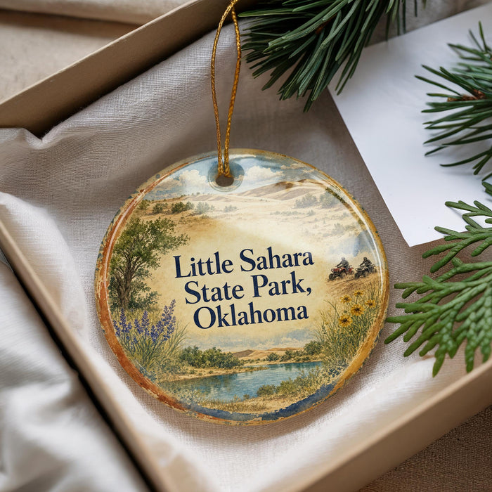 A decorative ornament with a landscape scene and text that says "Little Sahara State Park, Oklahoma" is displayed in a box with pine branches.