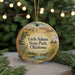 A round ornament with a scenic landscape of Little Sahara State Park, Oklahoma, featuring a river, mountains, and greenery.