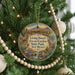 A circular ornament hanging on a Christmas tree, featuring an illustration of a desert landscape with a building and various desert animals.