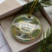 A decorative ornament in a box, featuring a scenic image of Long Branch State Park in Missouri.