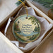 A decorative ornament in a box, featuring a lighthouse and a scenic landscape with a lake and a bench.