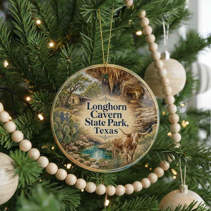 A circular ornament hanging on a Christmas tree, featuring an illustration of a scenic landscape with a large rock formation and a cow in the foreground.