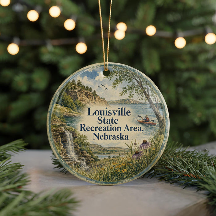 A round ornament with a scenic landscape of a lake, waterfall, and mountains, along with text that reads "Louisville State Recreation Area, Nebraska".