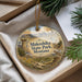 A decorative ornament with a landscape scene featuring mountains, pine trees, and wildlife, including a wolf, is displayed in a box.