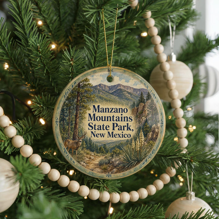 A round ornament hanging on a Christmas tree, featuring a scenic image of the Manzanos Mountains State Park in New Mexico.