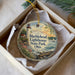 A decorative ornament in a box, featuring a lighthouse and a scenic landscape.