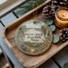 A wooden tray with a decorative ornament featuring a scenic landscape of Martin Dies Jr. State Park, Texas, and a candle on a table.