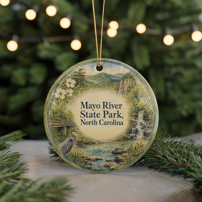 A round ornament with a scenic image of the Mayo River State Park in North Carolina, featuring a bird, a waterfall, and a bridge.